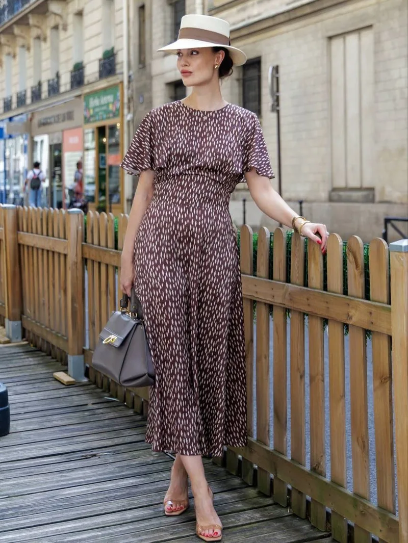 Model on a Paris terrace in a brown dash-print midi dress and straw boater