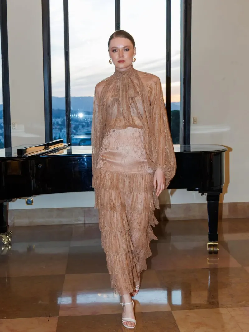 Model walking forward in the tiered caramel lace gown on a marble floor