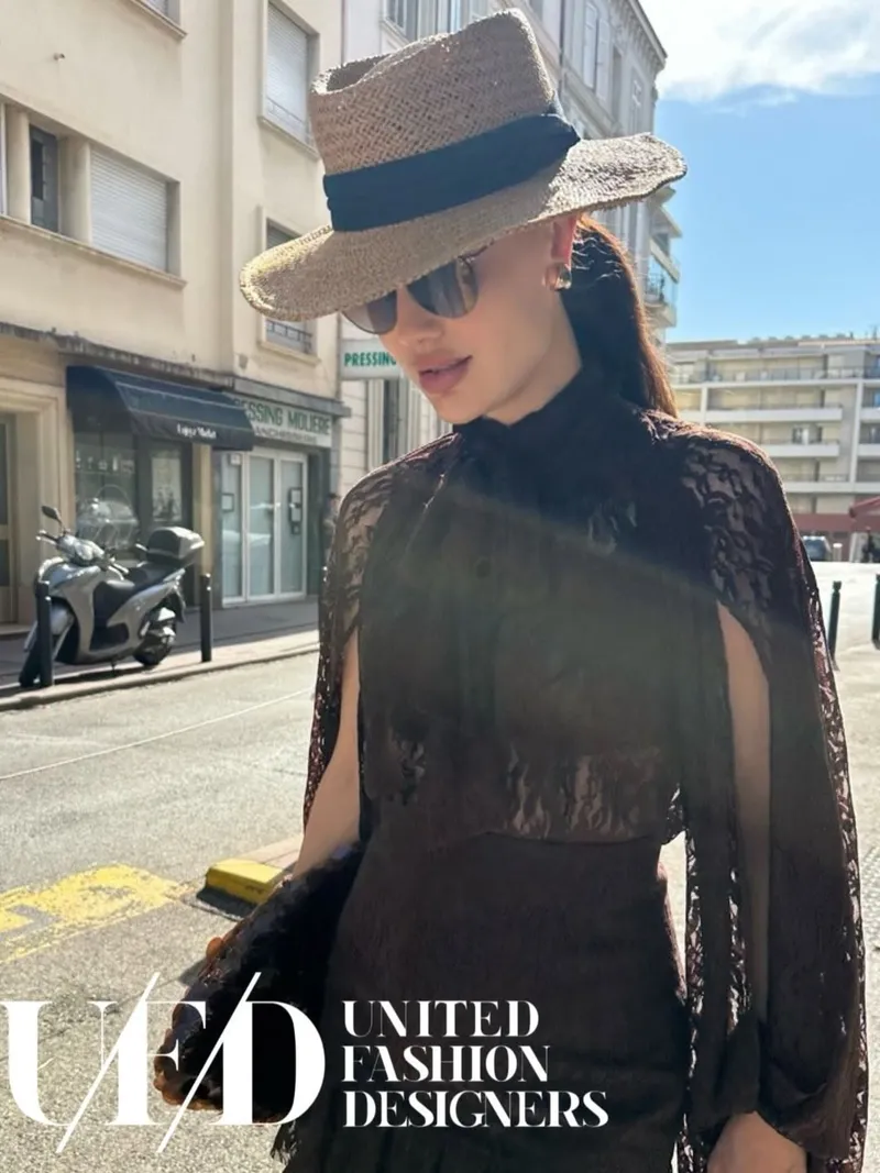 Street portrait in a wide straw hat and chocolate lace cape on a sunny avenue