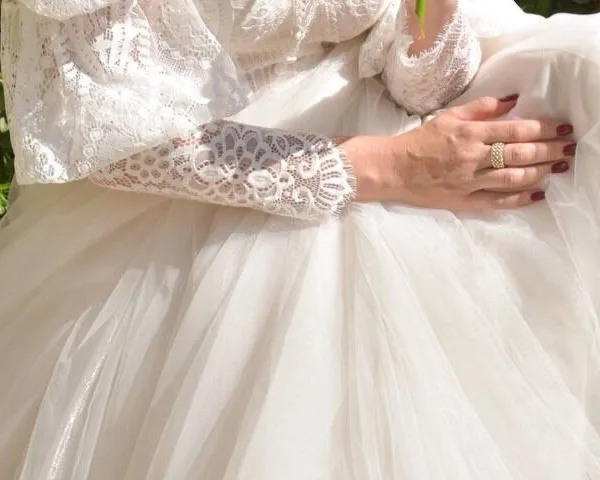 Detail of guipure lace sleeve and hand resting on tulle
