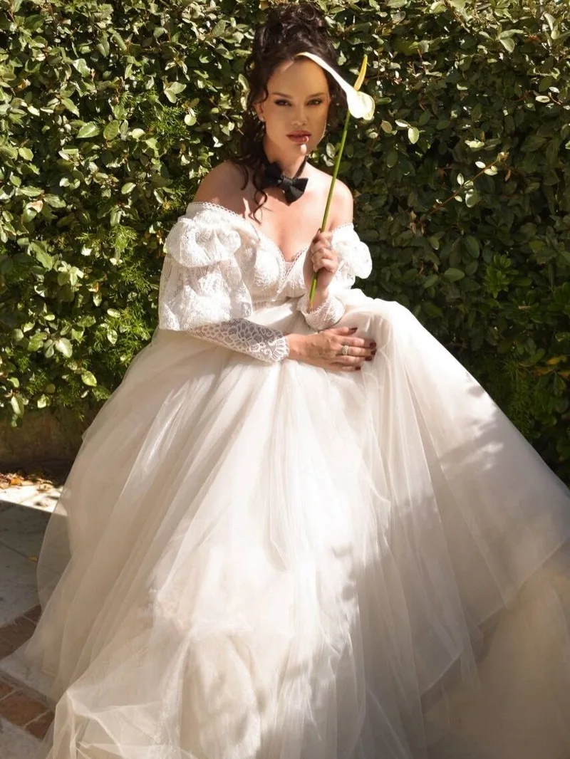 Seated model in an ivory lace bodice and voluminous tulle skirt in a sunlit garden