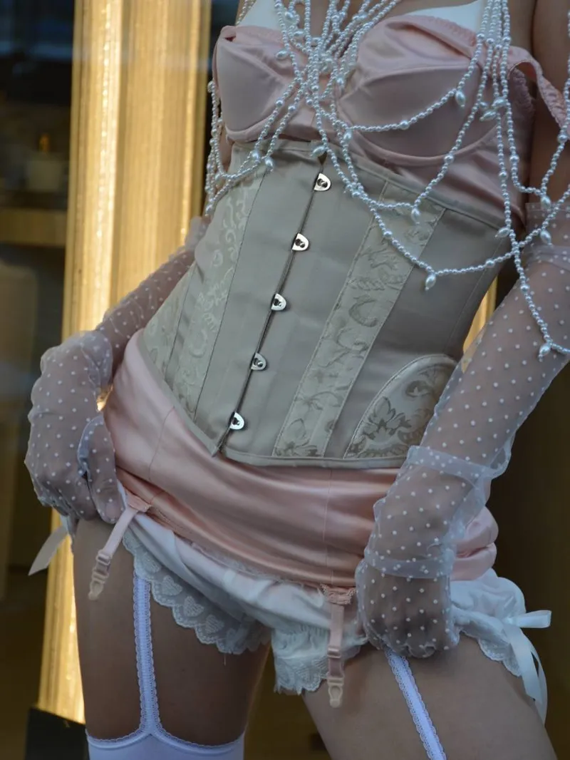 Detail of the champagne brocade underbust corset with front busk, pearl strands and polka-dot tulle gloves