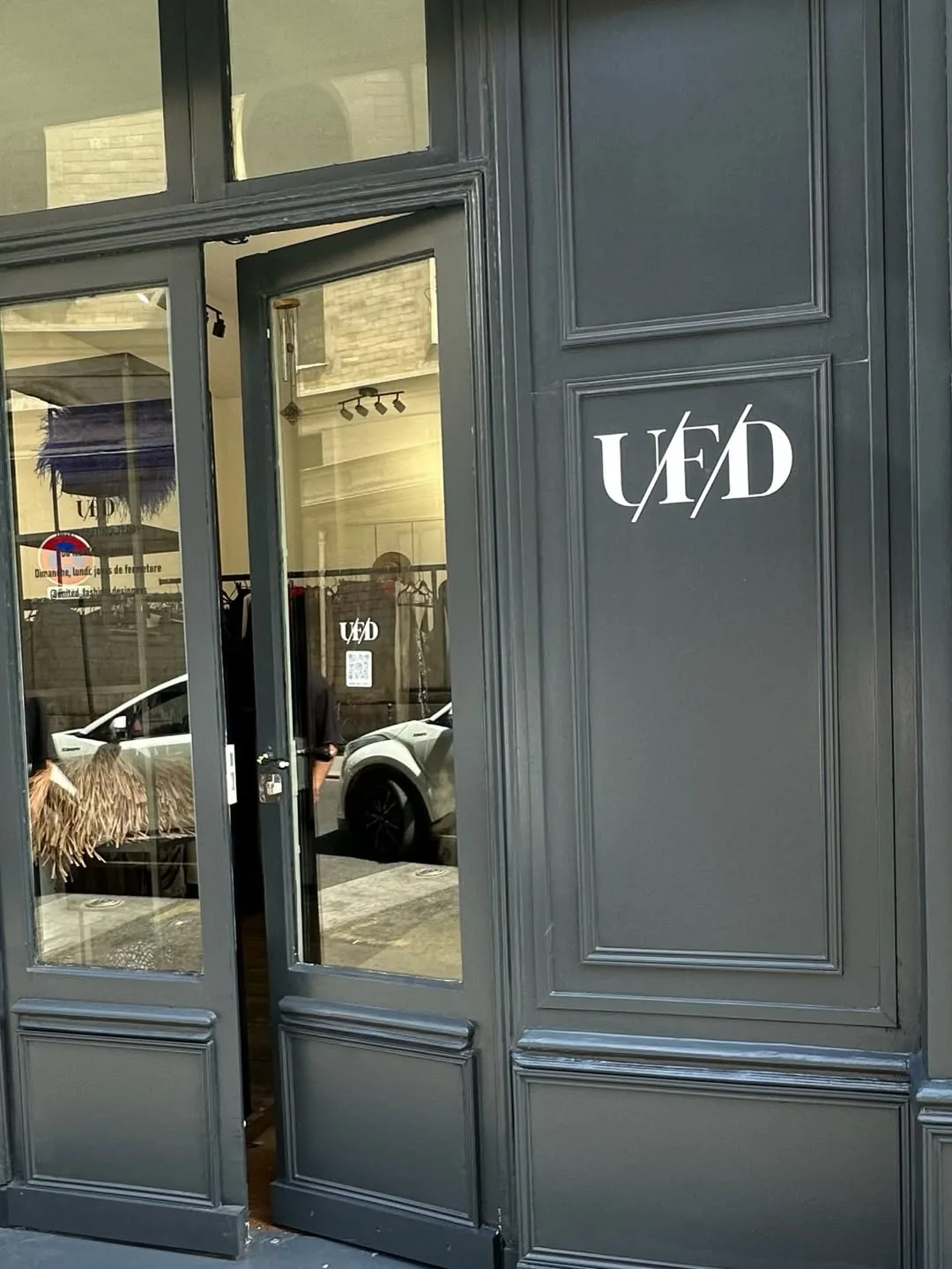 The UFD shopfront: charcoal panelled doors standing open, the white UFD monogram on the panel and rails of clothing inside