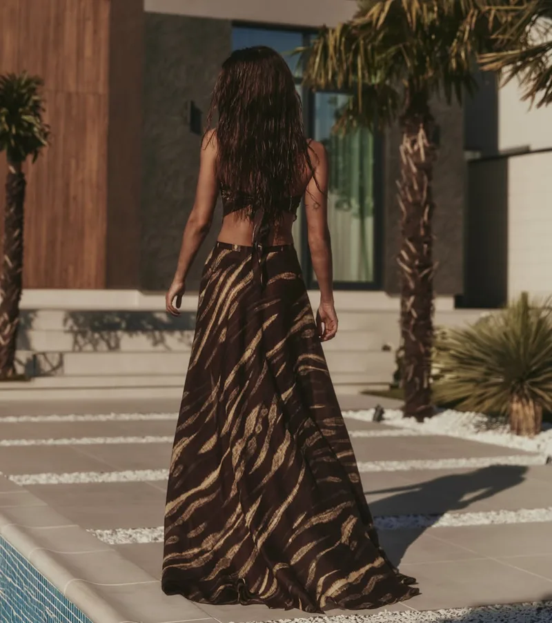 Back view of the striped wrap maxi skirt and tie-back bandeau beside palm trees