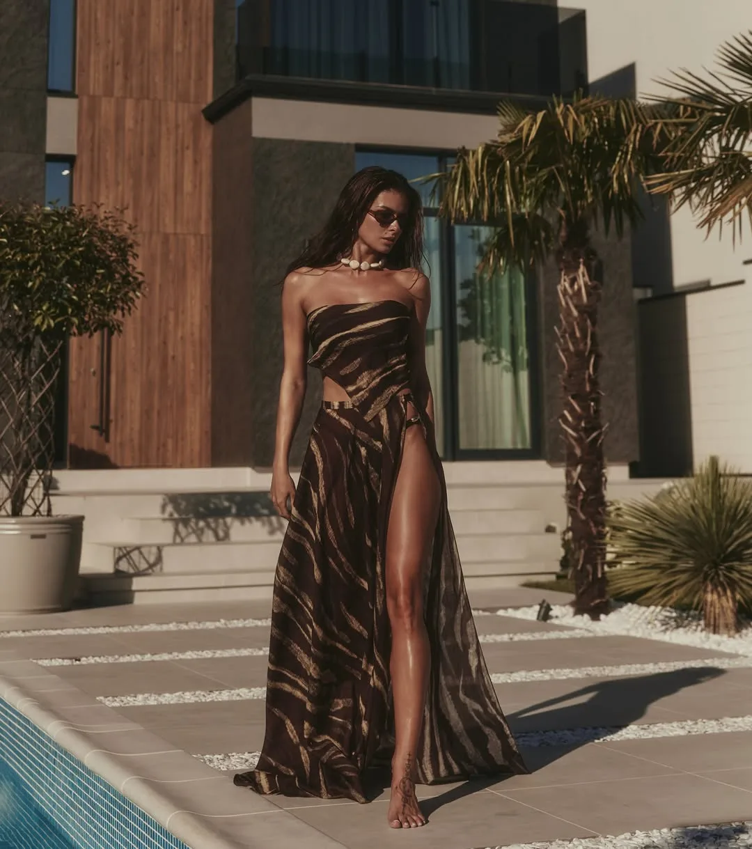 Model walking beside a pool in a striped bandeau top and high-split wrap maxi skirt